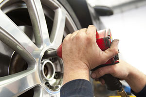 auto repairman worker in automotive industry using an air tool on a tire at auto repair shop